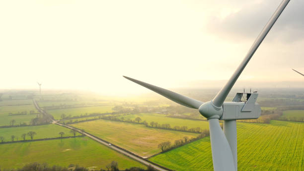 windkraftanlagen auf einem feld bei sonnenuntergang - windkraftanlage stock-fotos und bilder