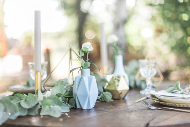 istock Table setting for an event party or wedding reception, decorated with geometric shape vases, gold candles eucalyptus branches and flowers. 1131449252