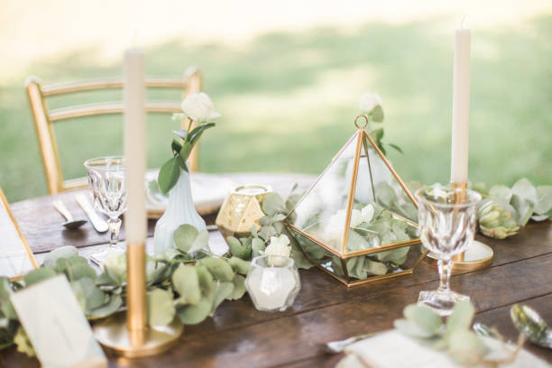 istock Gold and pastel wedding dinning table decoration. Geometic shapes, rustic decor, eucalyptus branches, candles, menu. Bokeh background. 1131449261
