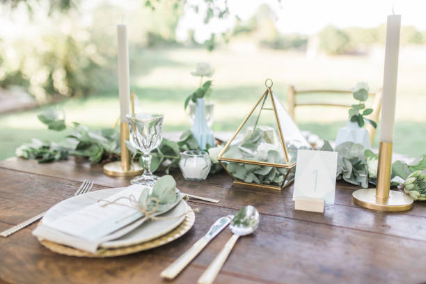 istock Table setting for an event party or wedding reception, decorated with geometric shape vases, gold candles eucalyptus branches and flowers. 1131449368
