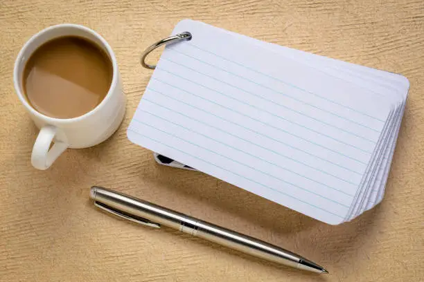 a stack of blank index cards with a cup of coffee and  a pen against textured bark paper