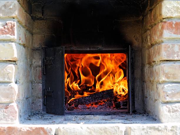 Close-up of intense flames and wood burning inside dark iron stove with visible inner firebox.
