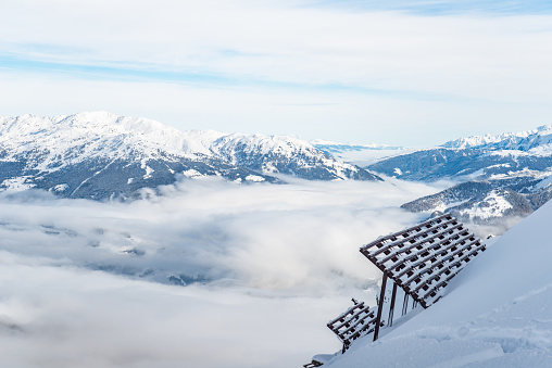 Skiiing at Zillertal - mountain snow Panorama with clouds and fog with blue sunny sky. Lawinenzaun.