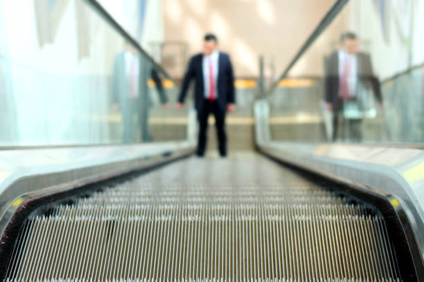 istock A man on an escalator staircase between a rise or fall between climb and fall 1131460654
