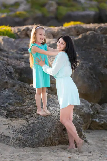 Photo of happy family at the beach. motherand child daughter hug at sunset