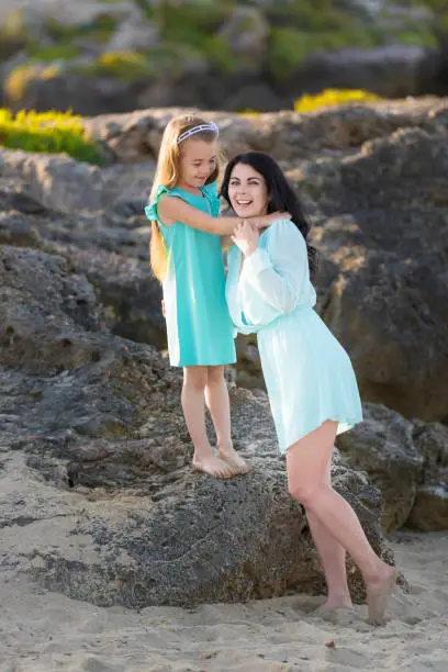 Photo of happy family at the beach. motherand child daughter hug at sunset