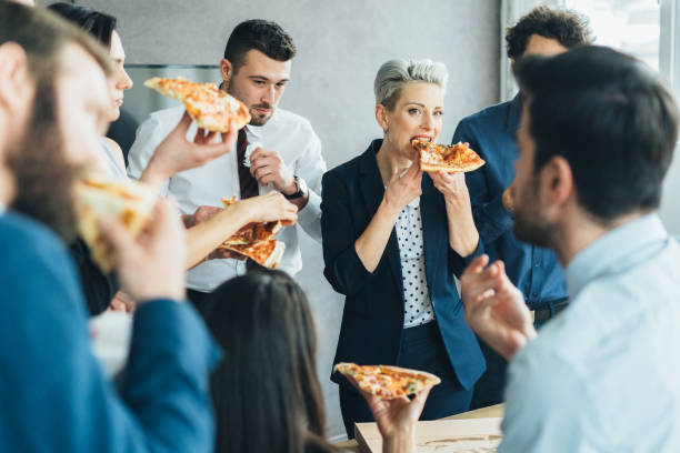 equipo de negocios comiendo pizza - pizza party fotografías e imágenes de stock