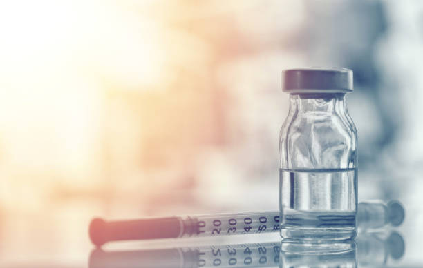 Closeup of medicine vial or flu, measles vaccine bottle with syringe and needle for immunization on vintage medical background, medicine and drug concept stock photo