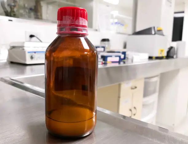 Photo of Liquid turbid chemical in an amber bottle in a scientific research laboratory