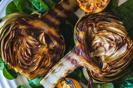 Grilled artichokes on a bed of spinach with grilled lemon halves