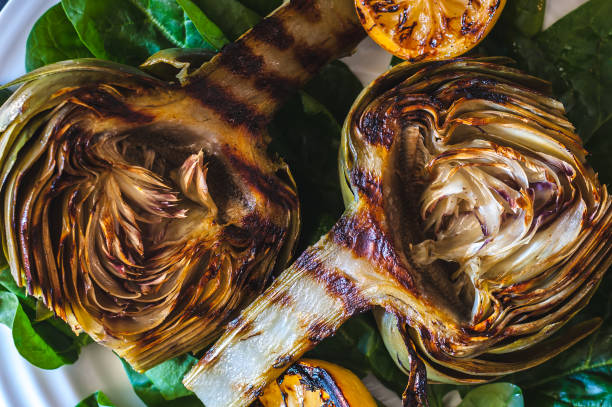 Grilled artichokes Grilled artichokes on a bed of spinach with grilled lemon halves artichoke stock pictures, royalty-free photos & images