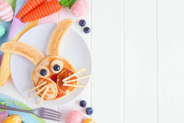 Easter Bunny pancake breakfast, side border with copy space against white wood Easter Bunny breakfast pancakes on a white plate. Side border against a white wood background with copy space. bunny pancake stock pictures, royalty-free photos & images