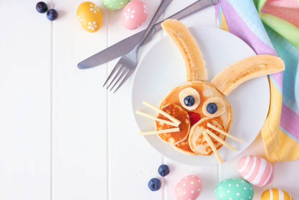 Easter Bunny pancake breakfast, corner border against a white wood background Cute Easter Bunny pancakes on a white plate. Corner border against a white wood background with copy space. bunny pancake stock pictures, royalty-free photos & images