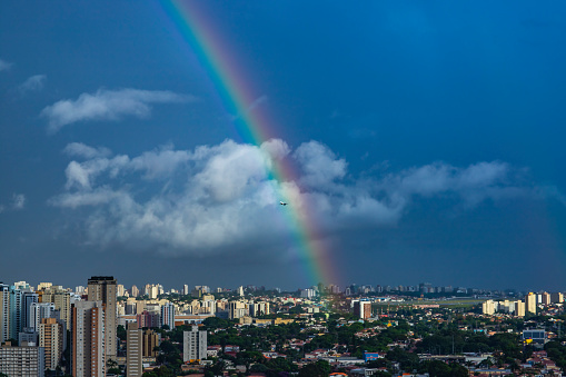 Rainbow and airplane in the city. Sao Paulo city, Brazil South America.