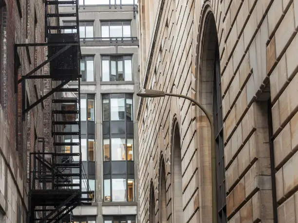 Photo of Fire escape stairs and ladder, in metal, on a typical North American old brick building from Montreal, Quebec, Canada. These stairs, made for emergency, are symbolic of the architecture