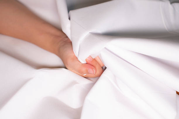 istock Woman hand squeezing bed sheets color white 1131509344