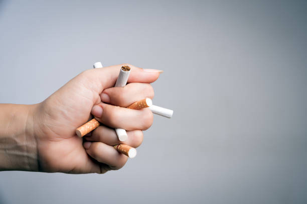 world no tobacco day, may 31. stop smoking. close up man hand crushing and destroying cigarettes on gray background. - nicotine healthcare and medicine smoking issues lifestyles imagens e fotografias de stock