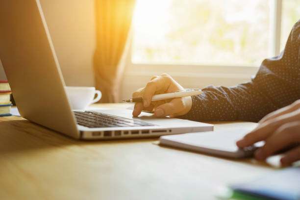 istock writing concept,man working at home office hand holding pen on keyboard ,student writes lectures study class in University campus,hipster man journal writer working on laptop computer ,vintage color 1131513391