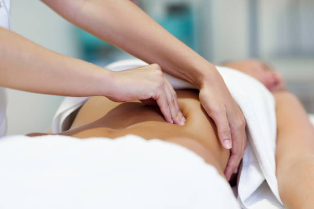 Woman having abdomen massage by professional osteopathy therapist stock photo