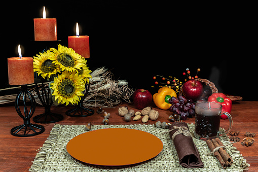 Thanksgiving setting for one with candle light, fruit, vegetables, hot tea, and sunflowers with cinnamon sticks and anise.