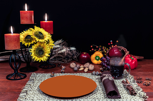 Thanksgiving setting for one with candle light, fruit, vegetables, hot tea, and sunflowers with cinnamon sticks and anise.