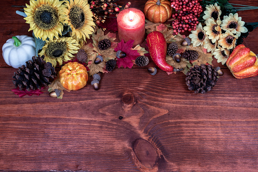 Thanksgiving decor with candle, pine cones, sunflowers, acorns, pumpkins, squash, guard, berries and maple leaves