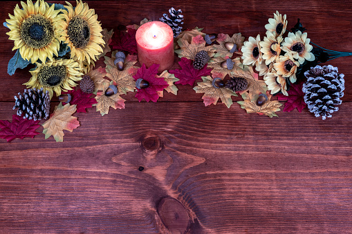 Thanksgiving decor with candle, frosted pine cones, sunflowers, acorns and maple leaves