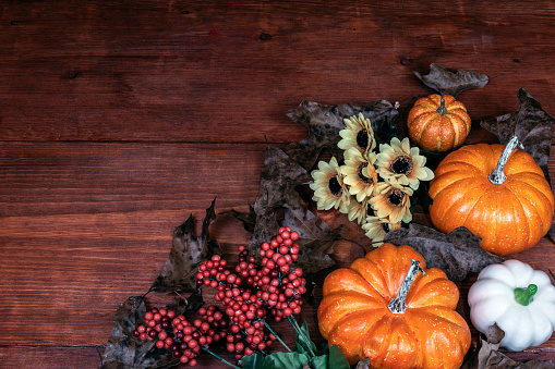 Thanksgiving decor with candle, pine cones, sunflowers, acorns, pumpkins, squash, guard, berries and  leaves.