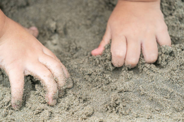 istock close up kid's hand and finger, play and learn at the beach. 1131521615