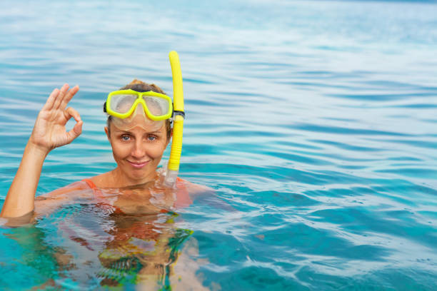 Young woman in snorkeling mask showing divers sign OK Young woman in snorkeling mask dive underwater with tropical fishes in coral reef sea pool. Show by hands divers sign OK. Travel lifestyle, water activity, beach adventure on summer holiday with child scuba diving family stock pictures, royalty-free photos & images
