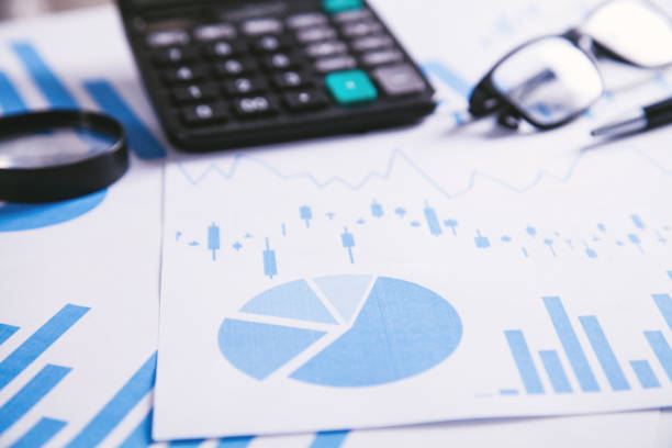 istock Calculator, pen and glasses with financial graphs. 1131524541