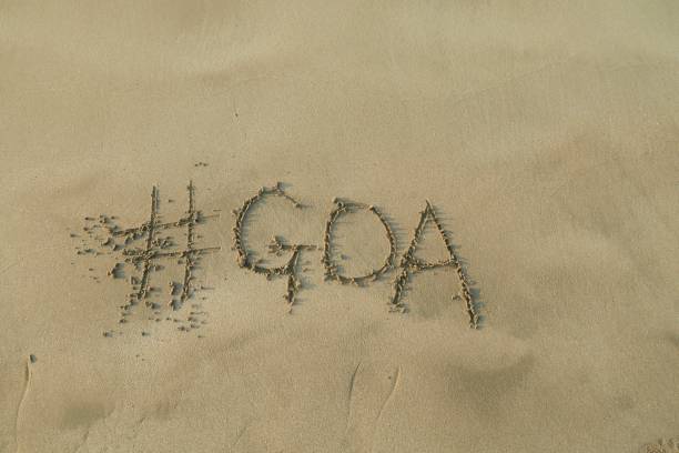 Image of hashtag tag writing on sunny beach in the soft sand, light by the early morning sunshine. Written using a stick by hand, with Goa words as capital letters by the gentle lapping waves of the sea on the seashore. Picture taken at Palolem Beach, Goa, India, during the early morning golden hour without tourists on holiday vacation / beachgoers. Concept photo of Goa handwriting in golden sand with modern hashtag prefix imagen de la escritura de etiqueta de hashtag en la playa soleada con palabras de goa escritas en arena por mar, playa palolem, goa, india, concepto de la foto de medios sociales de la escritura en la arena dorada con el hashtag moderno prefiix