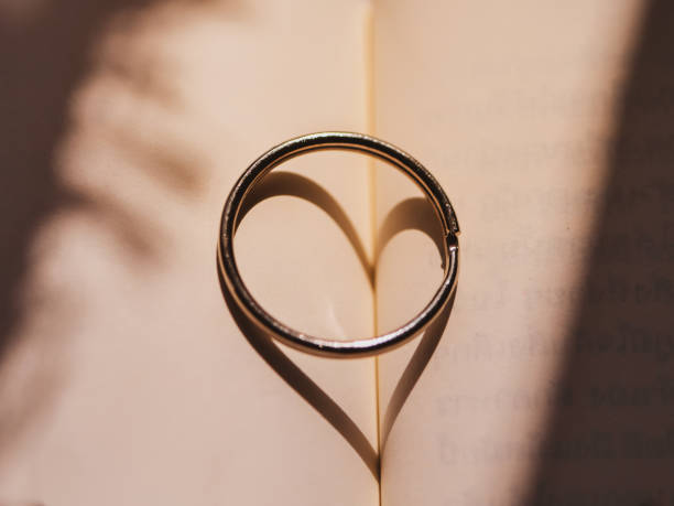 istock Heart sign form ring shadow on book, love concept. 1131530473