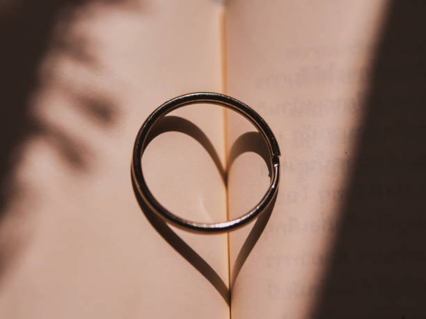 istock Heart sign form ring shadow on book, love concept. 1131530476
