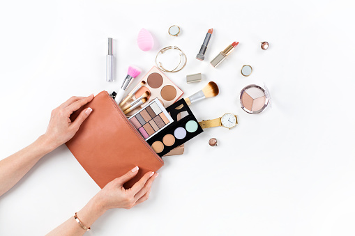 Female hands hold makeup bag with cosmetic beauty products