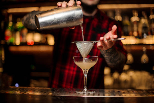 istock Barman pouring juicy alcoholic cocktail from shaker into cocktail glass using strainer 1131536706