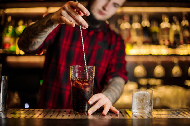 Barman stirring fresh strong alcoholic cocktail in a big glass Barman stirring fresh strong alcoholic cocktail in a big glass on the bar counter of restaurant bittersweet berry stock pictures, royalty-free photos & images