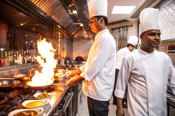 グルメレストランのプロのキッチンで調理するインドのシェフ - flambe ストックフォトと画像