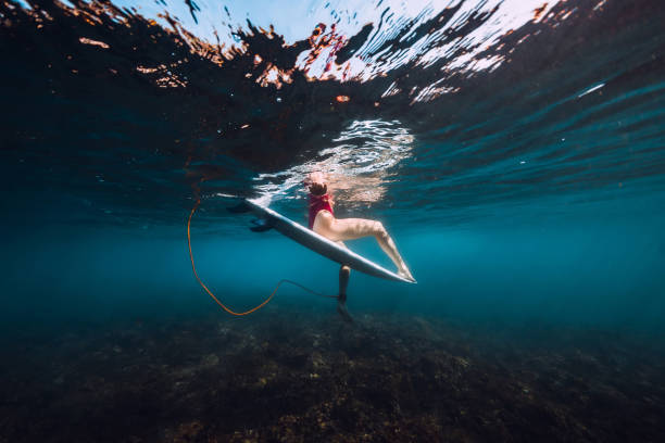istock Young surf girl at surfboard underwater in ocean 1131539228