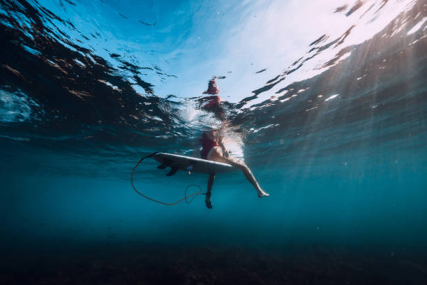 istock Young surf girl at surfboard underwater in ocean 1131539287