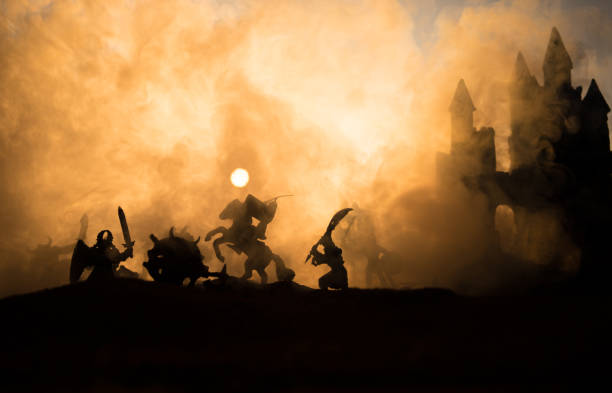 istock Medieval battle scene with cavalry and infantry. Silhouettes of figures as separate objects, fight between warriors on sunset foggy background. 1131540147