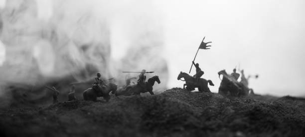 istock Medieval battle scene with cavalry and infantry. Silhouettes of figures as separate objects, fight between warriors on sunset foggy background. 1131540150