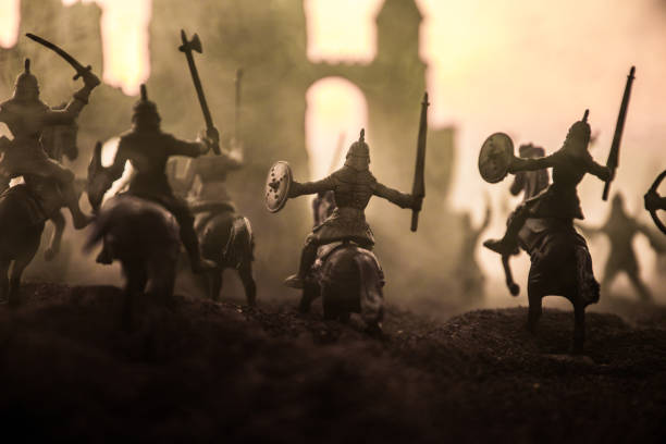 istock Medieval battle scene with cavalry and infantry. Silhouettes of figures as separate objects, fight between warriors on sunset foggy background. 1131540154