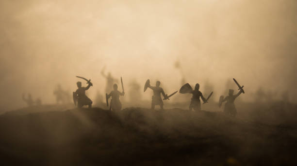 istock Medieval battle scene with cavalry and infantry. Silhouettes of figures as separate objects, fight between warriors on sunset foggy background. 1131540159
