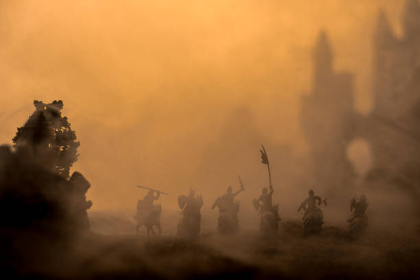 istock Medieval battle scene with cavalry and infantry. Silhouettes of figures as separate objects, fight between warriors on sunset foggy background. 1131540161