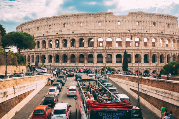 roma, itália. coliseu. ônibus turístico red hop on hop off para passear na rua perto do anfiteatro flaviano. marco famoso do unesco do mundo. excursão turística pela cidade. - southern europe public transportation international landmark local landmark - fotografias e filmes do acervo