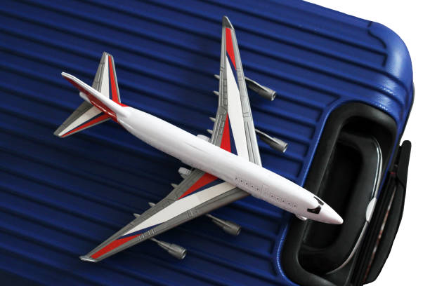 istock Blue suitcase and toy grey airplane, isolated. 1131540550
