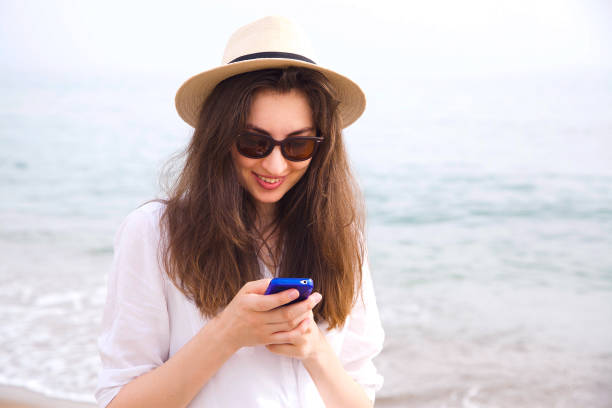 istock A hipster girl using her mobile phone on the beach. 1131544461