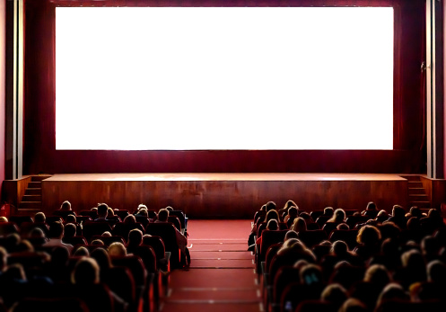 People in the cinema auditorium with empty white screen.