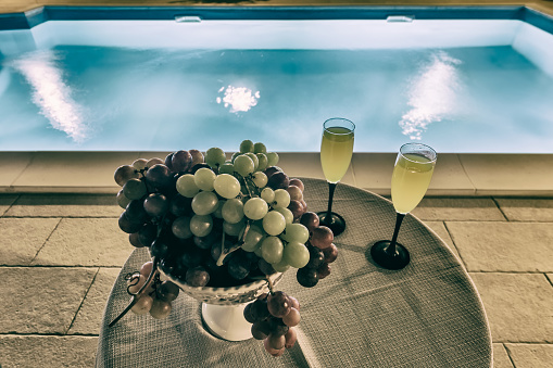 bowl with grapes and fresh drink near pool